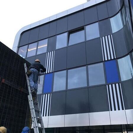 Ein Mann bringt eine Folie an einer Fassade an