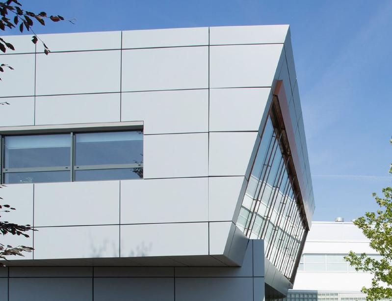 Ein Gebäude mit weißen Metallpaneelen, das modern und minimalistisch wirkt
